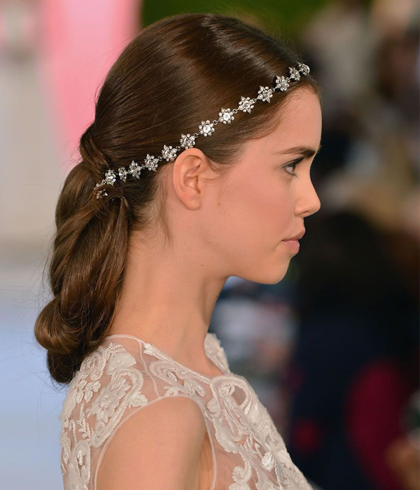 تسريحة كعكة الذيل حصان المزينة بتاج مرصع بالفصوص اللامعة للعروس من Oscar de la Renta ربيع 2015